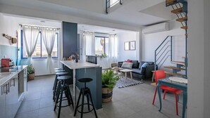 A modern apartment with a kitchen, dining area, and living room. There are stools at the kitchen counter, a sofa in the living room, and a staircase. - Port city haifa- beachfront complex (Haifa)
