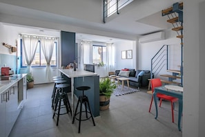 A modern apartment with a kitchen, dining area, and living room. There are stools at the kitchen counter, a sofa in the living room, and a staircase. - Port city haifa- beachfront complex (Haifa)