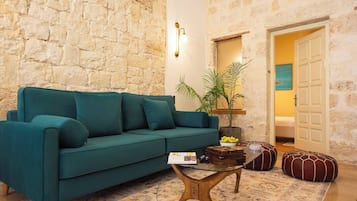 A cozy living room with a teal sofa, a coffee table, and a stone wall.