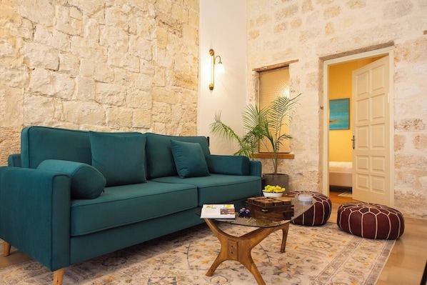 Una sala acogedora con un sofá color turquesa, una mesa de centro y una pared de piedra.
