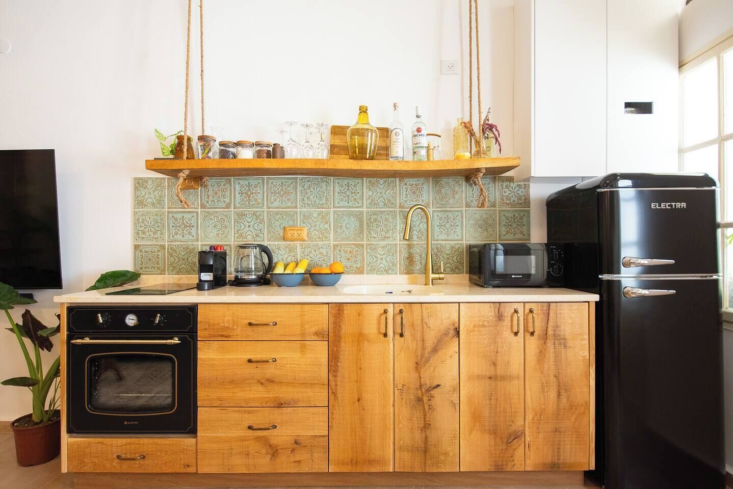 A kitchen with a black refrigerator, a coffee maker, a microwave, and a wooden cabinet with drawers.