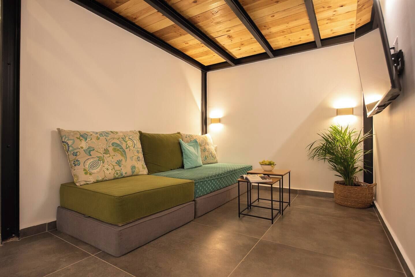 Una habitación acogedora con un sofá verde, una mesita y una planta en maceta.