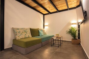 Una habitación acogedora con un sofá verde, una mesita y una planta en maceta.