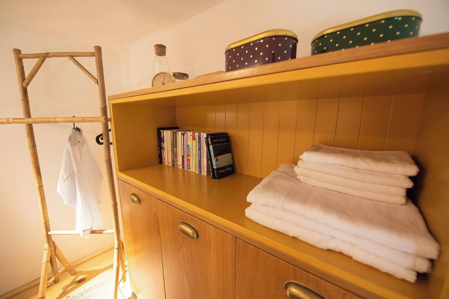 Une armoire en bois avec une étagère où sont pliées des serviettes et une rangée de livres.