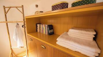 Une armoire en bois avec une étagère où sont pliées des serviettes et une rangée de livres.