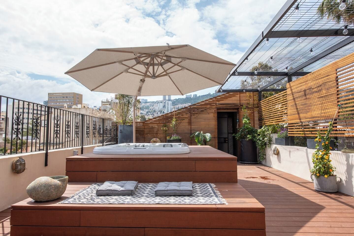 A rooftop terrace with a hot tub, outdoor seating, and a pergola.