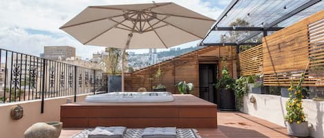 A rooftop terrace with a hot tub, outdoor seating, and a pergola.