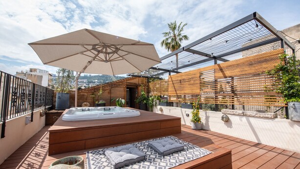 En tagterrasse med jacuzzi, udendørs møbler og et pergola