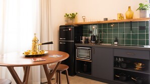 Et moderne køkken med indbygget ovn, kaffemaskine og spiseplads med bord og stole.