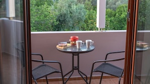 Un balcon avec deux chaises, une petite table et une bougie rouge.