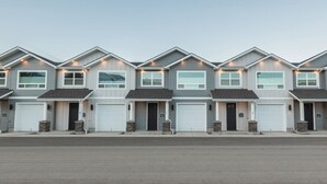 Uma fileira de casas modernas, com dois andares, garagens anexas e um caminho de acesso plano.