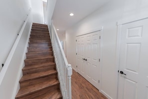 A staircase with wooden steps and white railings, leading to a hallway with white doors and a white ceiling. - Mountain View Townhome E| Walk to Downtown Joseph (Joseph)