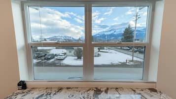A room with a large window offering a view of a snowy landscape and mountains.