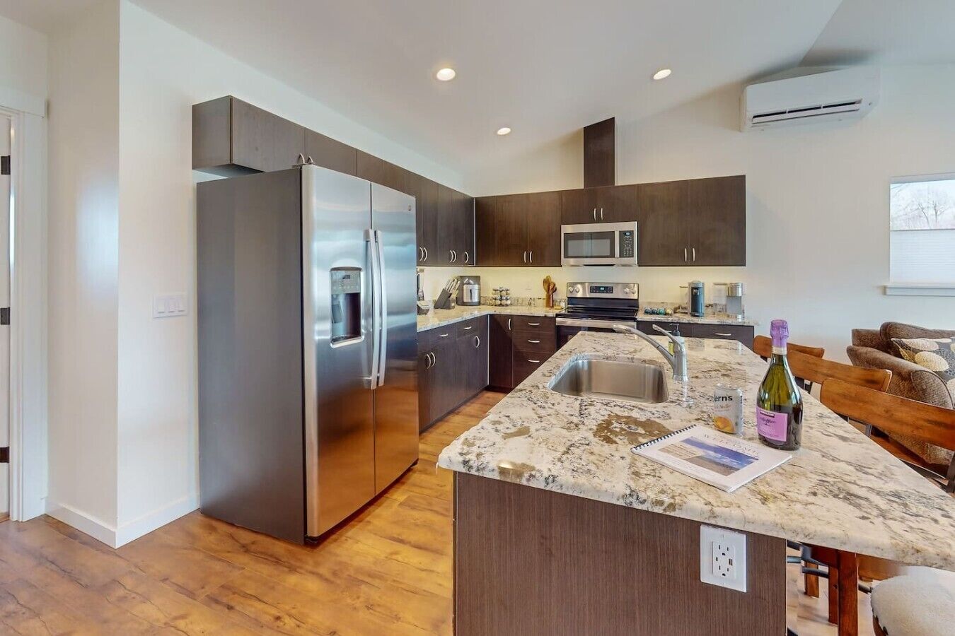 A modern kitchen with a large island, stainless steel appliances, and dark cabinetry.