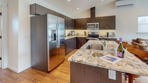 A modern kitchen with a large island, stainless steel appliances, and dark cabinetry.