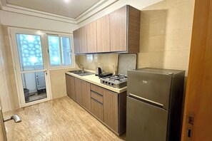 A compact kitchen with wooden cabinets, a stainless steel refrigerator, and a gas stove. - 2 Bedroom Apartment Sea View 🌊 + Free Parking | Rabat (Rabat)