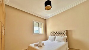 A bedroom with a large bed, a window, and a ceiling light. - 2 Bedroom Apartment Sea View 🌊 + Free Parking | Rabat (Rabat)
