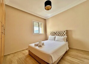 A bedroom with a large bed, a window, and a ceiling light. - 2 Bedroom Apartment Sea View 🌊 + Free Parking | Rabat (Rabat)