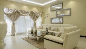 A modern living room with a white sofa, a glass coffee table, and a large mirror on the wall. - The Landmark Suites (Nairobi)