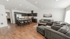 A modern living space with a kitchen, bar stools, a sofa set, and a painting on the wall. - Mountain View Townhome B |Walk to Downtown Joseph (Joseph)