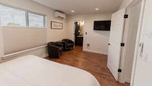 A bedroom with a large bed, two armchairs, a TV, and a door leading to a bathroom. - Mountain View Townhome B |Walk to Downtown Joseph (Joseph)