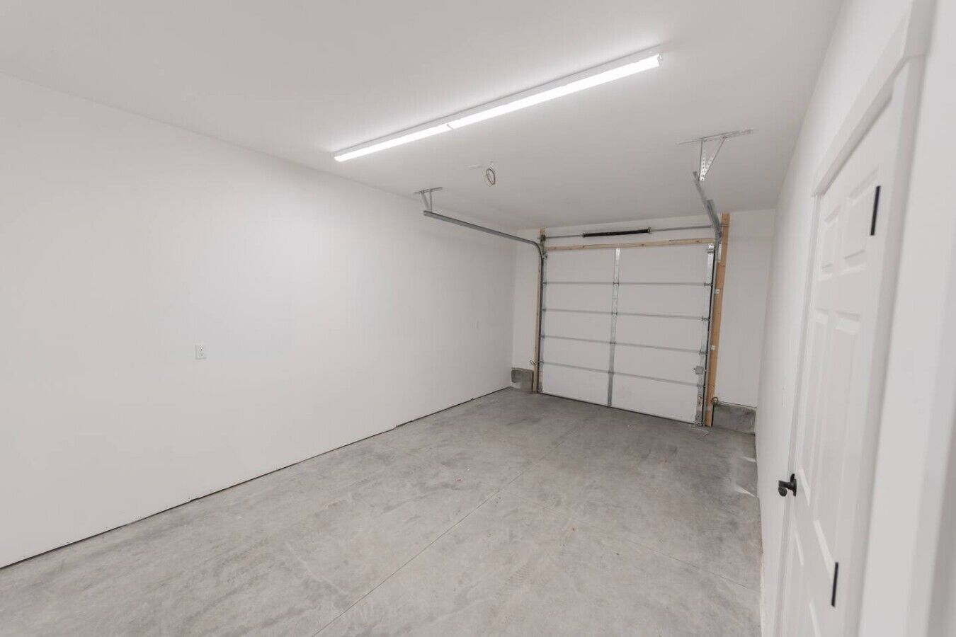A clean, empty garage with a concrete floor and white walls.