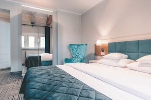 A hotel room with a bed, a chair, a nightstand, and a mirror. - Aparthotel Fortune (Poznań)