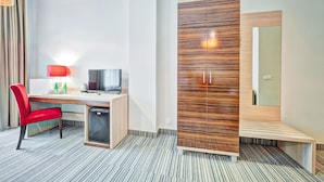 A hotel room with a desk, a red chair, a wardrobe, and a mirror. - Aparthotel Fortune (Poznań)
