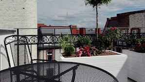 A rooftop terrace with a round metal table, a potted plant, and a brick wall. - Aparthotel Fortune (Poznań)
