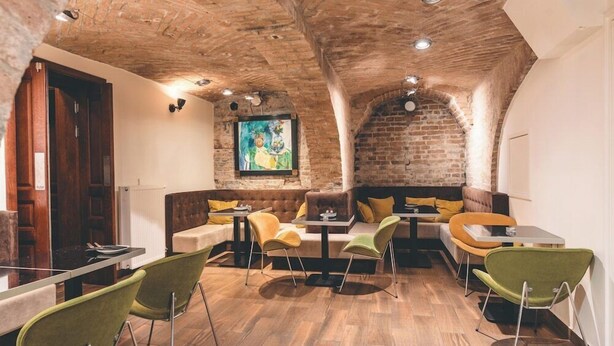 A cozy restaurant with a rustic brick ceiling, wooden tables, and green chairs. - Aparthotel Fortune (Poznań)