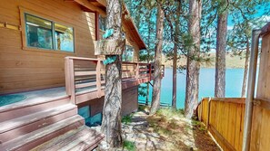 A cabin with a wooden deck, a small porch, and a view of a lake.