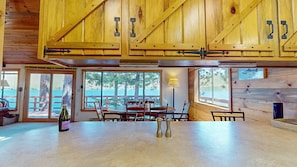 Un interior de madera con comedor, ventanas amplias y vistas al exterior.