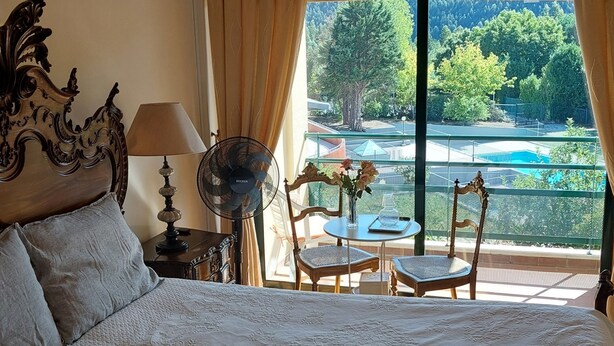 A hotel room with a large bed, a table with chairs, a fan, and a view of a swimming pool and trees. - DREAM HOUSE at Douro Valley with river view at 30Kms of Porto (PENAFIEL)
