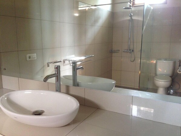 A modern bathroom with a large white sink, a mirror, and a glass-enclosed shower area. - Air Sanih Beach Villa (Kubutambahan)