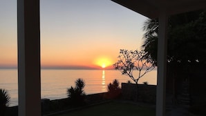 A sunset view from a covered outdoor area with a view of the sea. - Air Sanih Beach Villa (Kubutambahan)