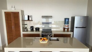 A modern kitchen with a central island, a stove, a sink, and a refrigerator. - Air Sanih Beach Villa (Kubutambahan)