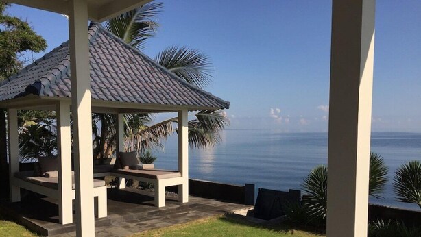 A covered outdoor seating area with a view of the ocean. - Air Sanih Beach Villa (Kubutambahan)