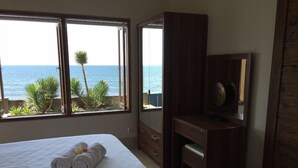 A bedroom with a bed, a desk, and a view of the ocean. - Air Sanih Beach Villa (Kubutambahan)