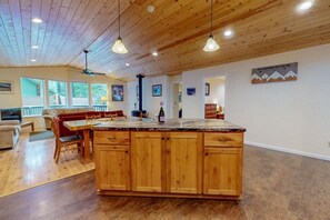 A spacious kitchen with wooden cabinets, a granite countertop, and pendant lighting.
