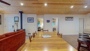 A spacious dining area with a long wooden table, chairs, and a red sofa. - Perfect Getaway for Up to 8 Guests | Glacier Lake (Joseph)