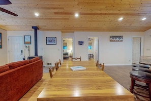 A spacious dining area with a long wooden table, chairs, and a red sofa.