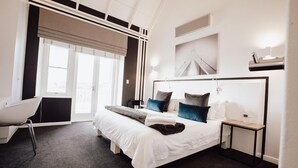 Una habitación de hotel moderna con una cama grande, un escritorio y una ventana con persianas.