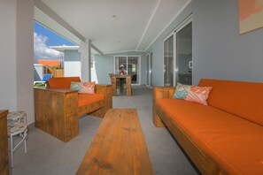 Ein zeitgemäßer Außenbereich mit einer Holzbank, einem orangefarbenen Sofa und einem kleinen Tisch.