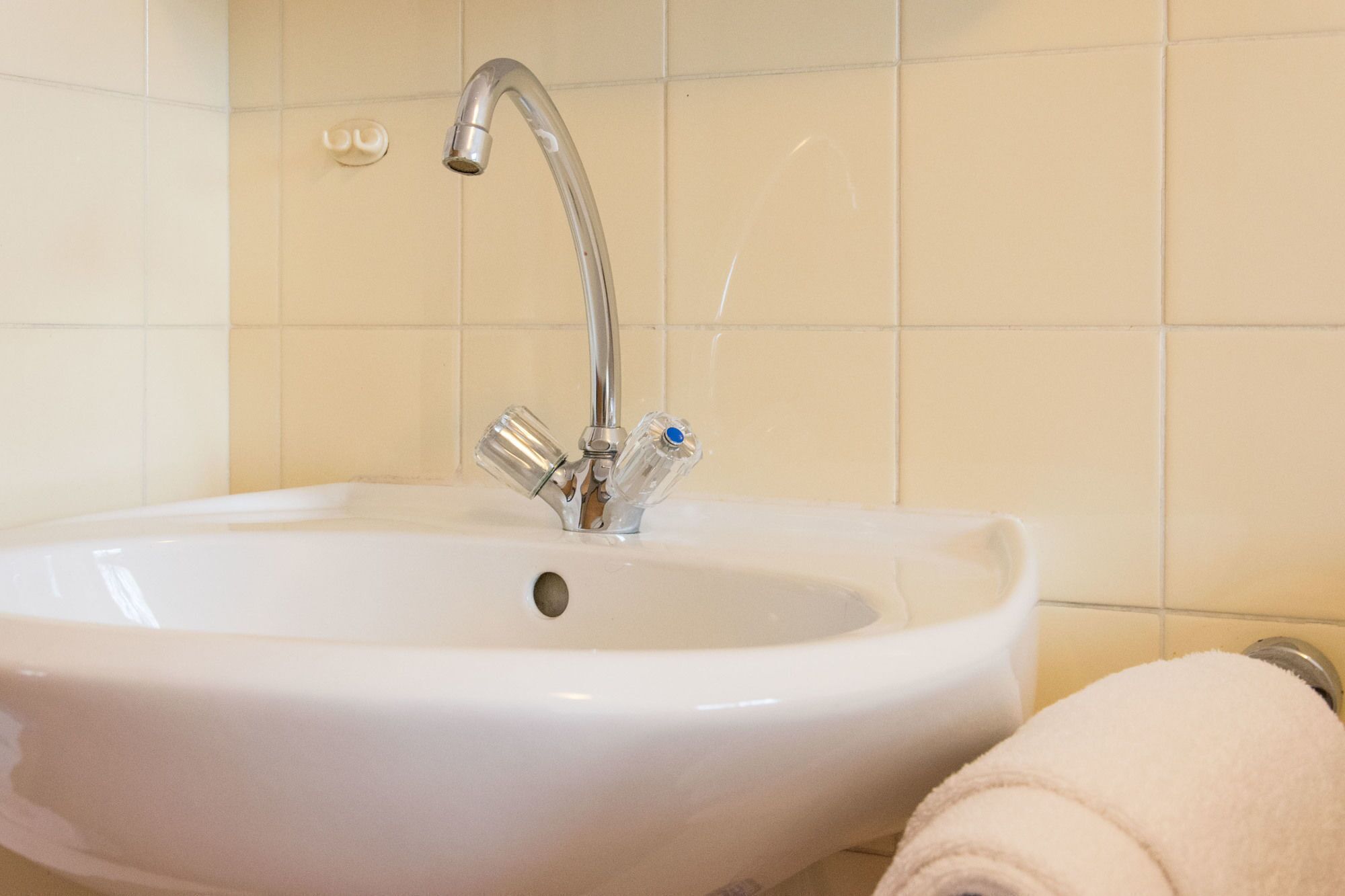 Ein weißes Waschbecken mit einem einzelnen Wasserhahn und einem Handtuch auf der rechten Seite.