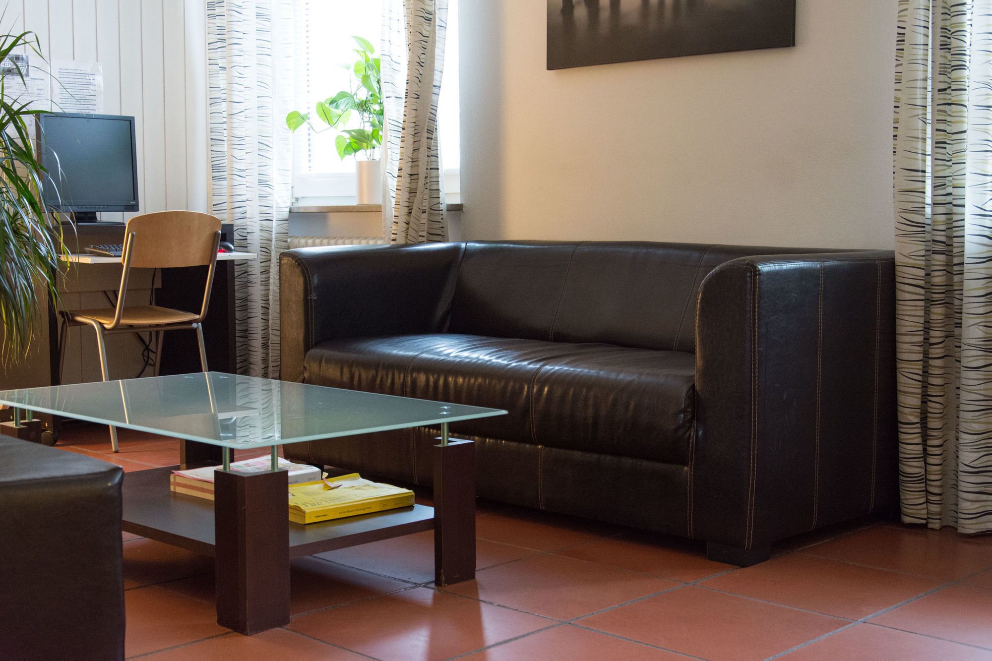 Un soggiorno con divano in pelle, tavolino in vetro, una poltrona e una televisione.
