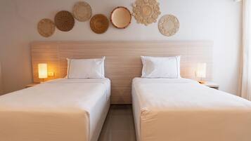 A hotel room with two beds, a wooden headboard, wall-mounted woven baskets, and bedside lamps.