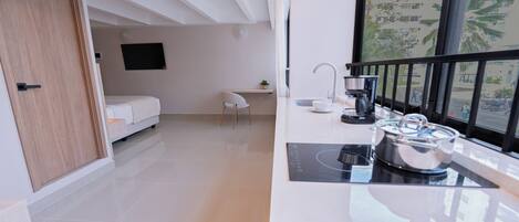 A modern kitchen with a built-in stove, a sink, and a window with a view of buildings and palm trees.