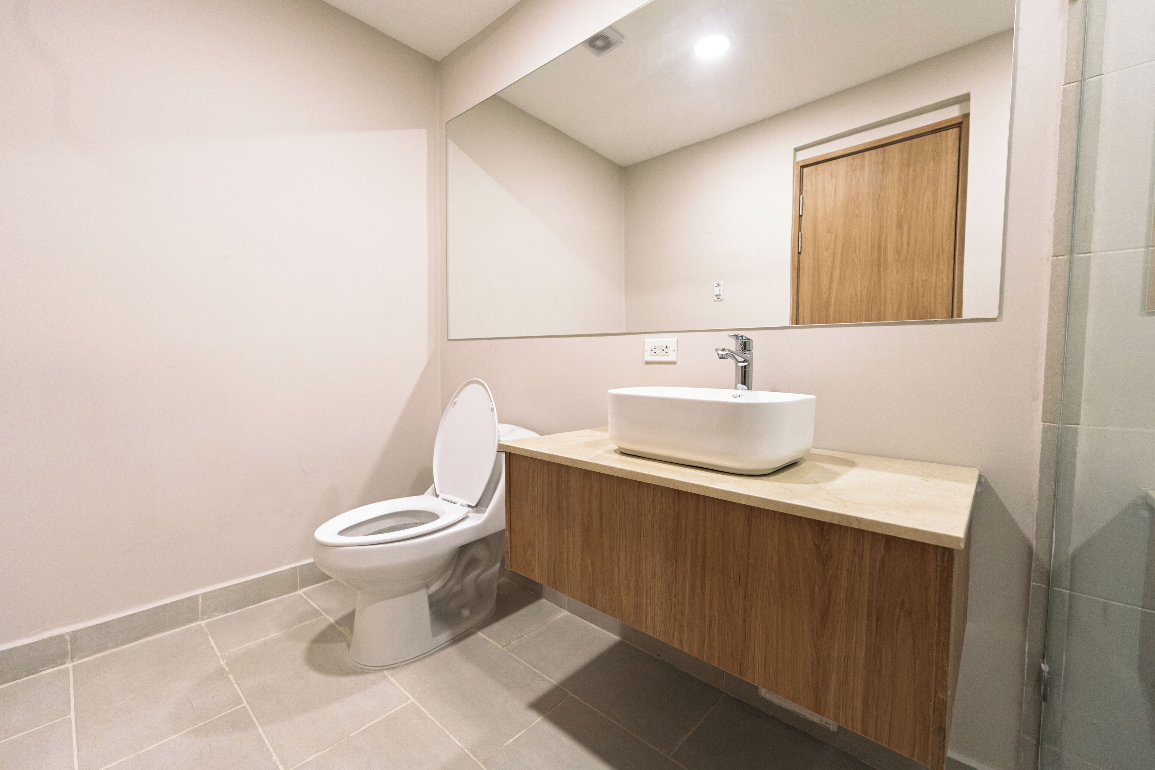 Un baño moderno con inodoro, lavabo, espejo y ducha.