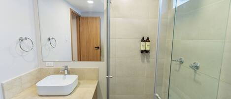 A modern bathroom with a glass-enclosed shower, a wooden vanity, and a large mirror.