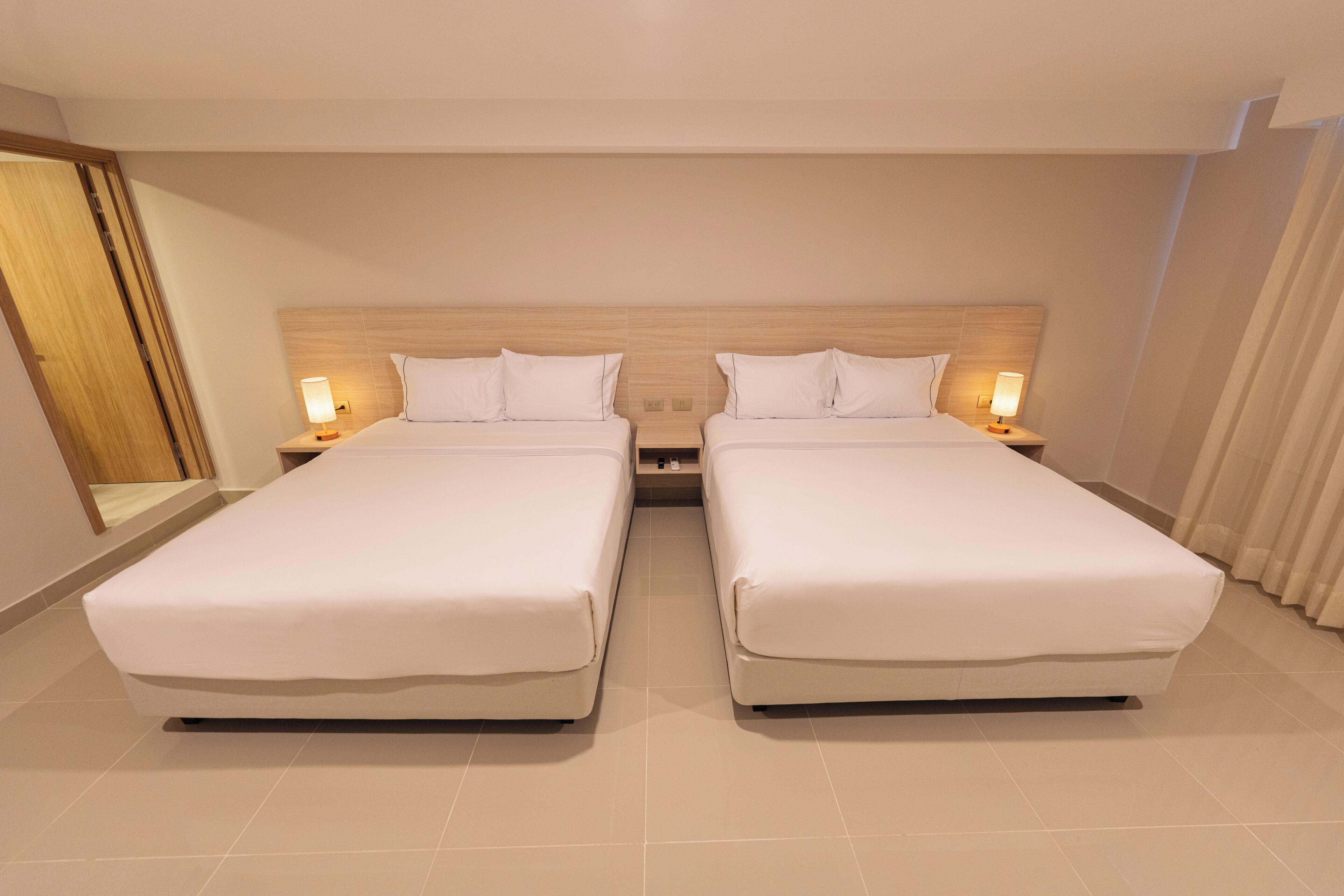 A hotel room with two beds, a wooden headboard, bedside lamps, and a large mirror.